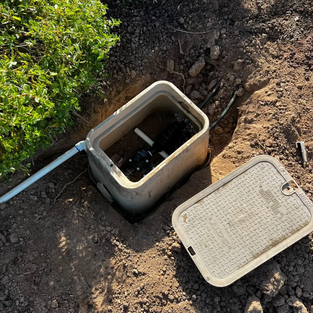 Valve box opened up for a repair — new PVC run in and the lid off to the side before backfill.