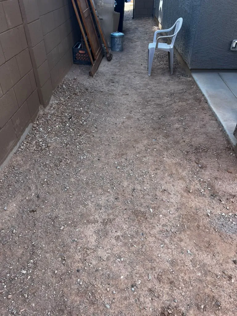 Side yard cleared down to bare dirt and raked out — the starting point before border and gravel go in.